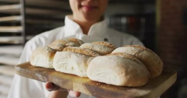 Asyalı kadın fırıncının taze ekmek ile panoyu tutmasının animasyonu. Pastanede çalışmak, bağımsız küçük işletme.