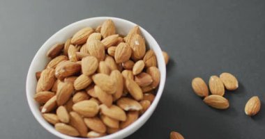 Gri arka planda bir kasede taze badem videosu. Taze vejetaryen yemeği, bitki temelli diyet, sağlıklı beslenme konsepti.