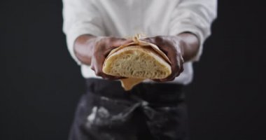 Aşçının siyah arka planda bir somun ekmeği tutuşu videosu. yemek ve yemek malzemeleri konsepti.