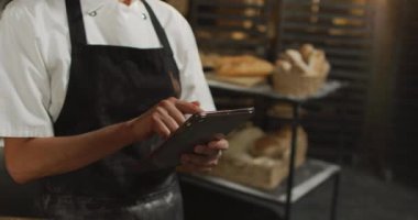 Tablet kullanan Asyalı fırıncının orta bölümünün animasyonu. Pastanede çalışmak, bağımsız küçük işletme.