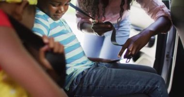 Animation of happy african american mother fastening belts in children seats in car. family, spending quality time together and traveling concept.