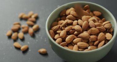 Gri arka planda bir kasede taze badem videosu. Taze vejetaryen yemeği, bitki temelli diyet, sağlıklı beslenme konsepti.