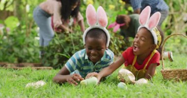 Mutlu Afro-Amerikan kardeşlerin paskalya yumurtalarıyla çimlerde yatması. Aile Paskalyası, kutlama ve birlikte dışarıda kaliteli zaman geçirmek..