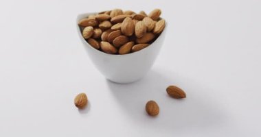 Beyaz arka planda bir kasedeki badem videosu. Taze vejetaryen yemeği, bitki temelli diyet, sağlıklı beslenme konsepti.