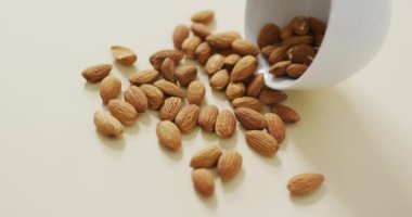 Beyaz arka planda bir kasedeki badem videosu. Taze vejetaryen yemeği, bitki temelli diyet, sağlıklı beslenme konsepti.