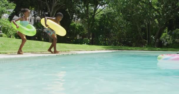Happy African American Siblings Jumping Pool Inflatable Wheels Family Togetherness — Video Stock