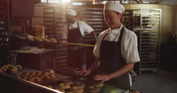 Animation Happy Asian Female Baker Arranging Croissants Tray Working Bakery — Stockvideo