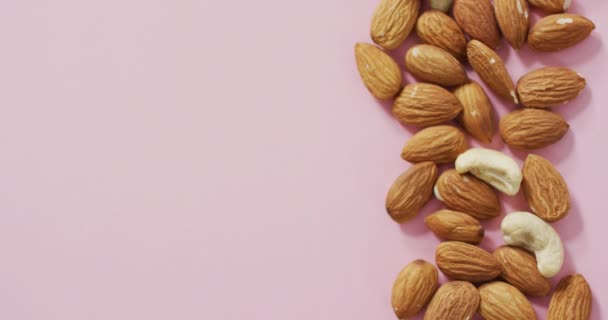 ピンクの背景にアーモンドとナッツのビデオ 新鮮なビーガンフード 植物ベースの食事 健康的な食事のコンセプト — ストック動画