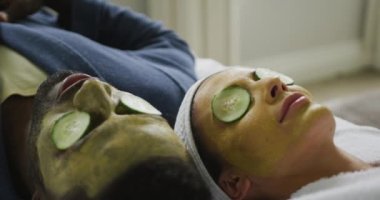 Maskeli ve gözlerinde salatalık parçalarıyla banyoda yatan mutlu çift. Evde birlikte vakit geçirmek..