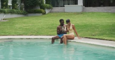 Bahçedeki havuzda mayo giyen ve içki içen mutlu çift. Evde birlikte vakit geçirmek..