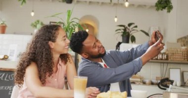 Kafede birlikte zaman geçirip, kahve içip selfie çeken mutlu bir çift. Küçük bağımsız kafe işletmesi.