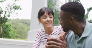 Bahçede bluz ve tişört giyen, konuşan ve kahve içen mutlu çift. Evde birlikte vakit geçirmek..