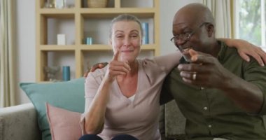 Gömlek giyen ve oturma odasında görüntülü konuşma yapan yaşlı çiftin portresi. Evde birlikte vakit geçirmek..