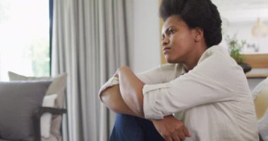 Düşünceli Afrikalı Amerikalı kadın oturma odasında kanepede oturuyor. ev hayatı, evde boş zaman geçirmek..