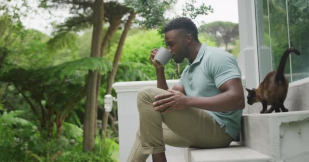 Felice Uomo Afroamericano Seduto Con Gatto Bere Caffè Giardino Passare — Video Stock