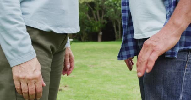 在花园里牵着手的高加索女性和男性老年朋友中间的动画 退休生活 与朋友共度美好时光 — 图库视频影像