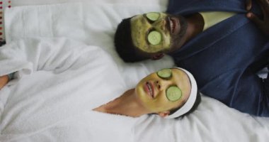 Maskeli ve gözlerinde salatalık parçalarıyla banyoda yatan mutlu çift. Evde birlikte vakit geçirmek..
