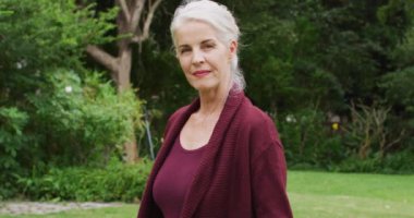 Bahçede kameraya gülümseyen beyaz yaşlı kadın animasyonu. Emeklilik hayatı, dışarıda boş zaman geçirmek..