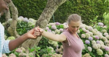 Mutlu kıdemli çift tişört giyip bahçede dans ediyor. Evde birlikte vakit geçirmek..