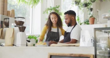 Afro-Amerikan erkek kafe sahibi ve kafede tablet kullanan melez kadın barista. Küçük bağımsız kafe işletmesi.