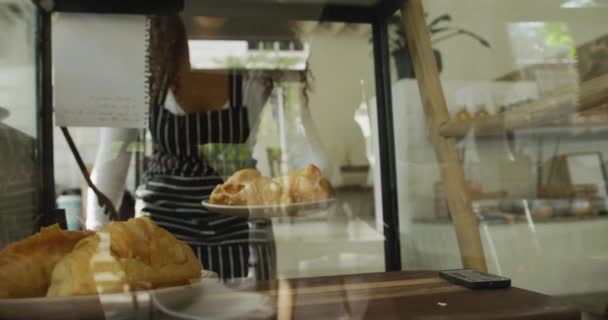 在咖啡店的橱窗里 愉快地拿着羊角面包在盘子里吃着 小型独立咖啡店 — 图库视频影像