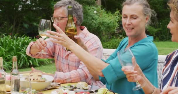 Animación Diversos Amigos Adultos Mayores Felices Almorzando Jardín Sirviendo Vino — Vídeos de Stock