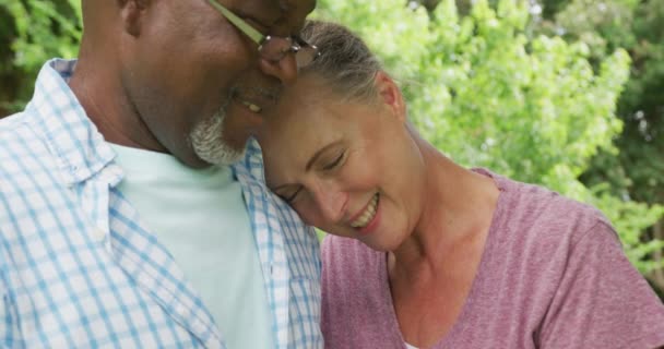 幸せな高齢者の多様なカップルのシャツを着て庭で抱擁 家で一緒に過ごす — ストック動画