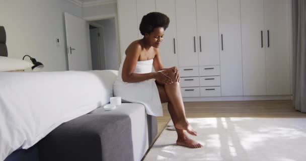 Happy Afro Amerikaanse Vrouw Aanbrengen Crème Benen Slaapkamer Binnenlandse Levensstijl — Stockvideo