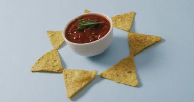 Gri bir yüzeyde tortilla cipsi ve salsa sosu videosu. parti yemekleri ve tuzlu atıştırmalıklar.