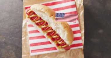 Hardallı sosisli sandviç ve siyah bir yüzeye Amerikan bayrağı konmuş ketçap. Yemek, yemek ve yemek malzemeleri..
