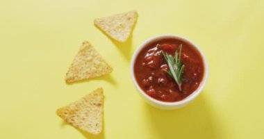 Tortilla cipsi ve salsa sosunun sarımsı bir yüzeye konduğu bir video. parti yemekleri ve tuzlu atıştırmalıklar.