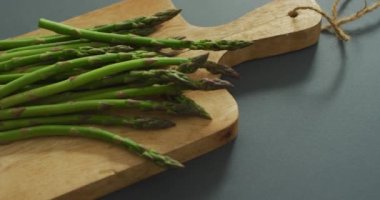 Gri arka planda ahşap kesim tahtasında kuşkonmaz videosu. Füzyon yiyecekler, taze sebzeler ve sağlıklı yeme konsepti.