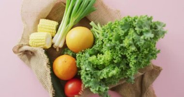 Pembe arka planda taze meyve ve sebzelerin olduğu bir video. Füzyon yemeği, taze meyve, sebze ve sağlıklı beslenme konsepti.