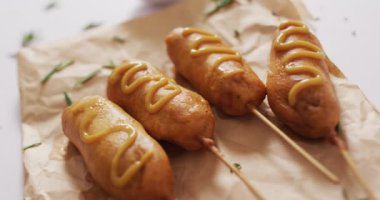 Beyaz bir yüzeye batırılmış mısırlı sosis videosu. Yemek, yemek ve yemek malzemeleri..