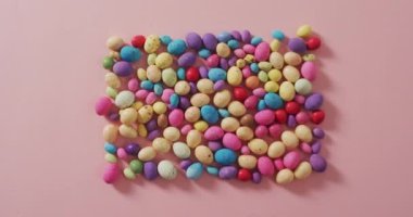 Pembe bir yüzey üzerindeki renkli paskalya yumurtalarının videosu. Geleneksel Paskalya tatlıları.