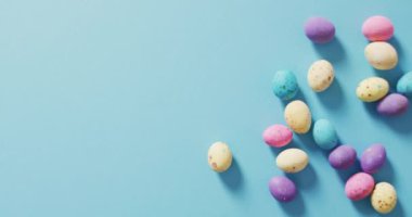 Mavi bir yüzey üzerindeki renkli paskalya yumurtalarının videosu. Geleneksel Paskalya tatlıları.