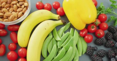 Taze meyve, sebze, fındık ve tohumların gri arka planda olduğu bir video. Füzyon yiyecekler, taze sebzeler ve sağlıklı yeme konsepti.