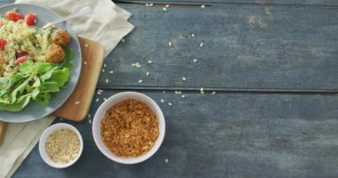 Yeşil yapraklı taze salata videosu ve ahşap zemin üzerinde tohumlar olan kaseler. Füzyon yiyecekler, taze sebzeler ve sağlıklı yeme konsepti.