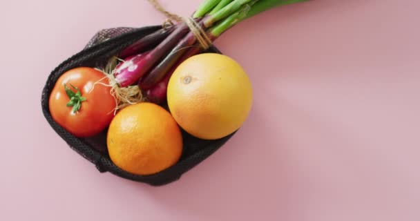 ピンクの背景に黒の袋に入っている新鮮な果物や野菜のビデオ 融合食品 新鮮な果物 野菜や健康的な食事の概念 — ストック動画