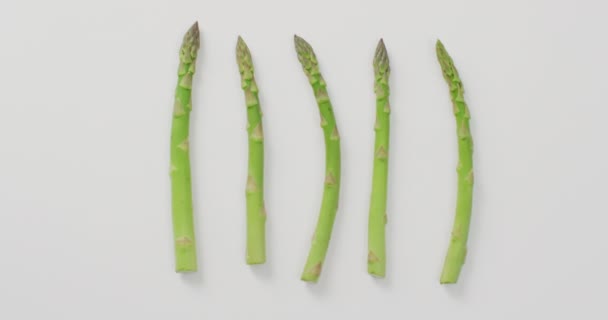 白い背景に5つの新鮮なアスパラガスの茎の終わりのビデオ 融合食品 新鮮な野菜や健康的な食事の概念 — ストック動画