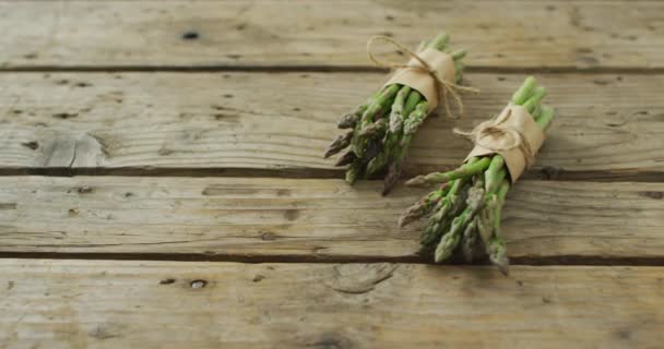 木製の背景に2つの新鮮なアスパラガスバンドルのビデオ 融合食品 新鮮な野菜や健康的な食事の概念 — ストック動画