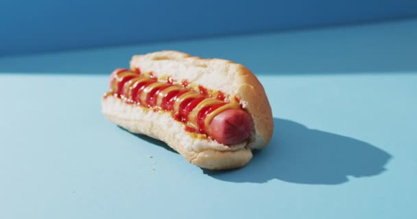 Video Hot Dog Con Mostaza Ketchup Sobre Una Superficie Azul — Vídeo de stock
