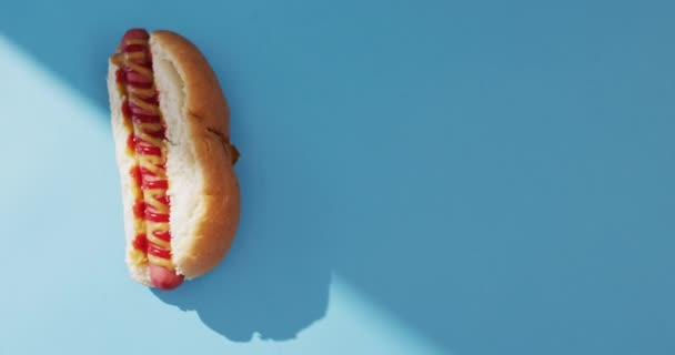Video Hot Dog Con Mostaza Ketchup Sobre Una Superficie Azul — Vídeo de stock