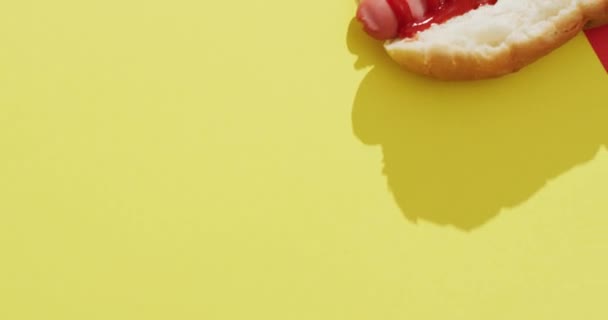 黄色と赤の表面にマスタードとケチャップでホットドッグのビデオ 食べ物料理ケータリング成分 — ストック動画