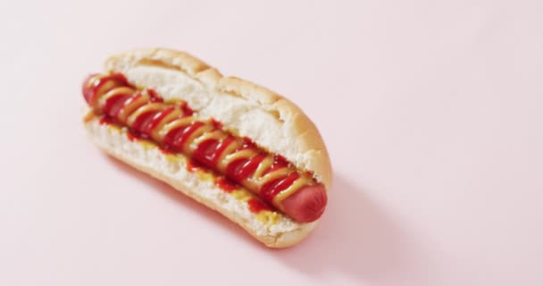 Video Hot Dog Con Mostaza Ketchup Sobre Una Superficie Rosada — Vídeo de stock