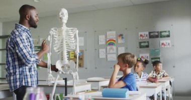 Anatomi dersi sırasında farklı sınıflardan öğrencileri olan mutlu bir Afrikalı Amerikan öğretmeninin videosu. İlkokul eğitimi ve öğretmenlik mesleği.