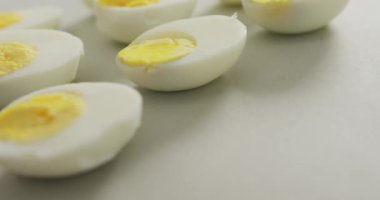 Gri arka planda kaynamış yumurtaların yarısının yakın çekim videosu. Füzyon yiyeceği, pişirme, yumurta ve paskalya konsepti.