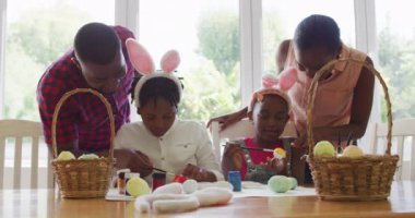Afro-Amerikan ailesi evde paskalya yumurtası boyuyor. Paskalya bayramı ruhu ve eğlence kavramı