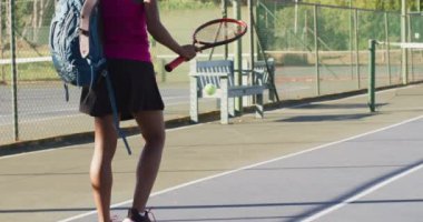 Video of back of african american female tennis player holding racket and bouncing ball. professional tennis training, sport and competition concept.