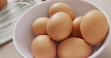 Video of close up of eggs and egg whisk on rustic cloth on beige background. fusion food, baking, eggs and easter concept.